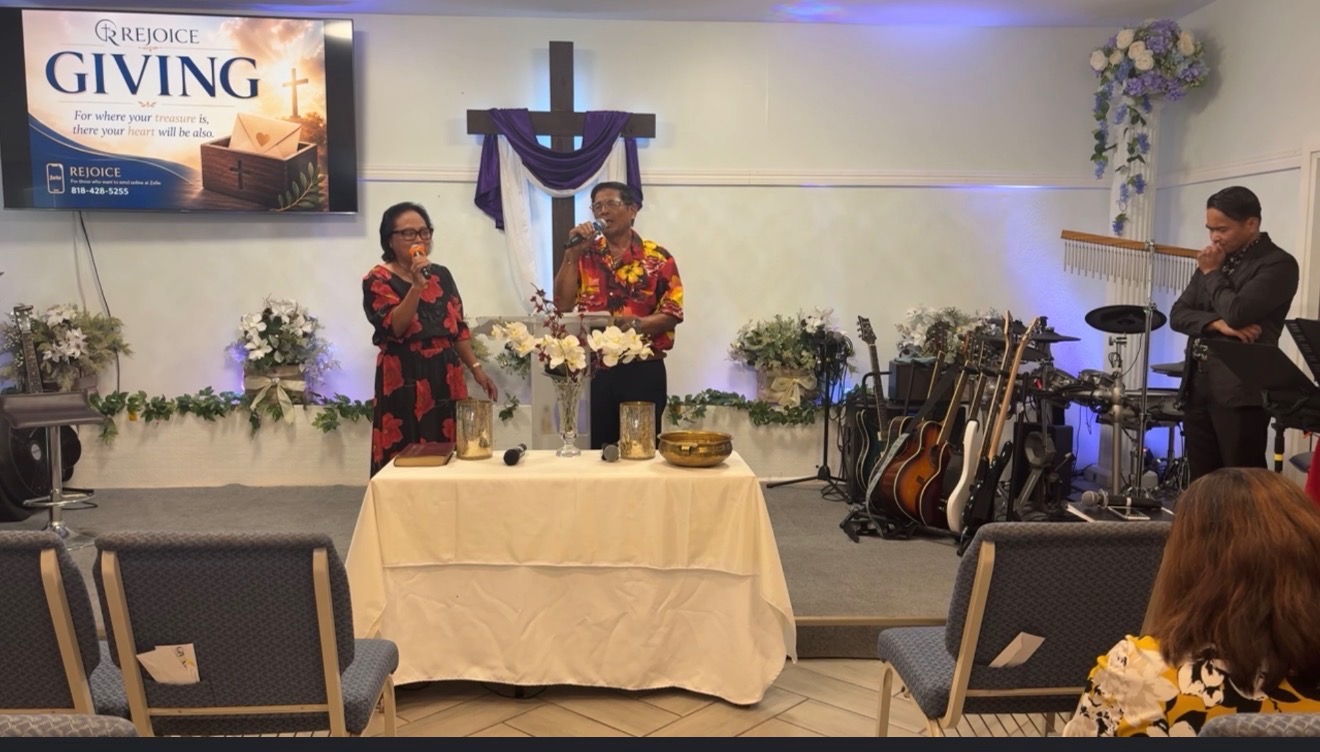 Sunday worship at Rejoice Christian Fellowship — the praise team leading songs while the congregation gathers in prayer